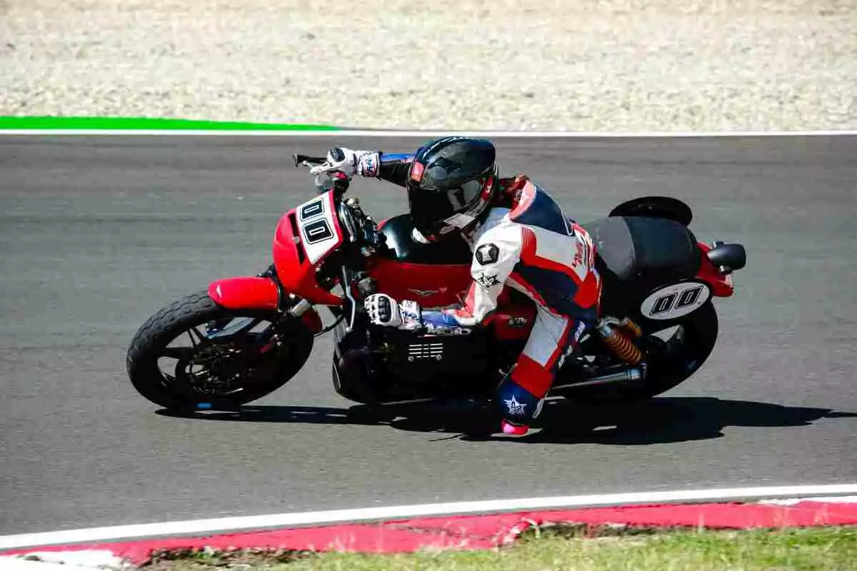 Motociclista con traje y casco de protección tomando una curva en una pista de carreras sobre una motocicleta roja con el número 00 Motociclista con traje y casco de protección tomando una curva en una pista de carreras sobre una motocicleta roja con el número 00