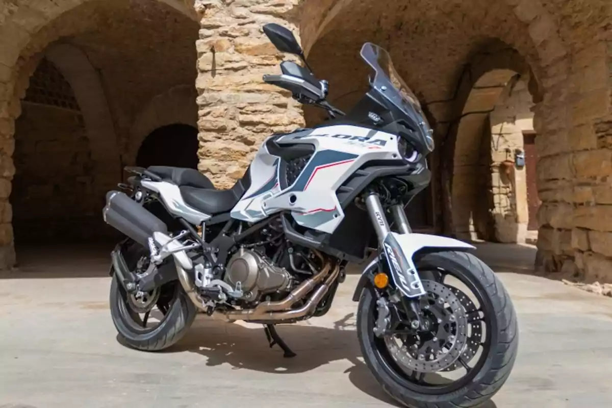 Motocicleta esportiva blanca estacionada davant d’una construcció de pedra amb arcs antics Motocicleta esportiva blanca estacionada davant d’una construcció de pedra amb arcs antics