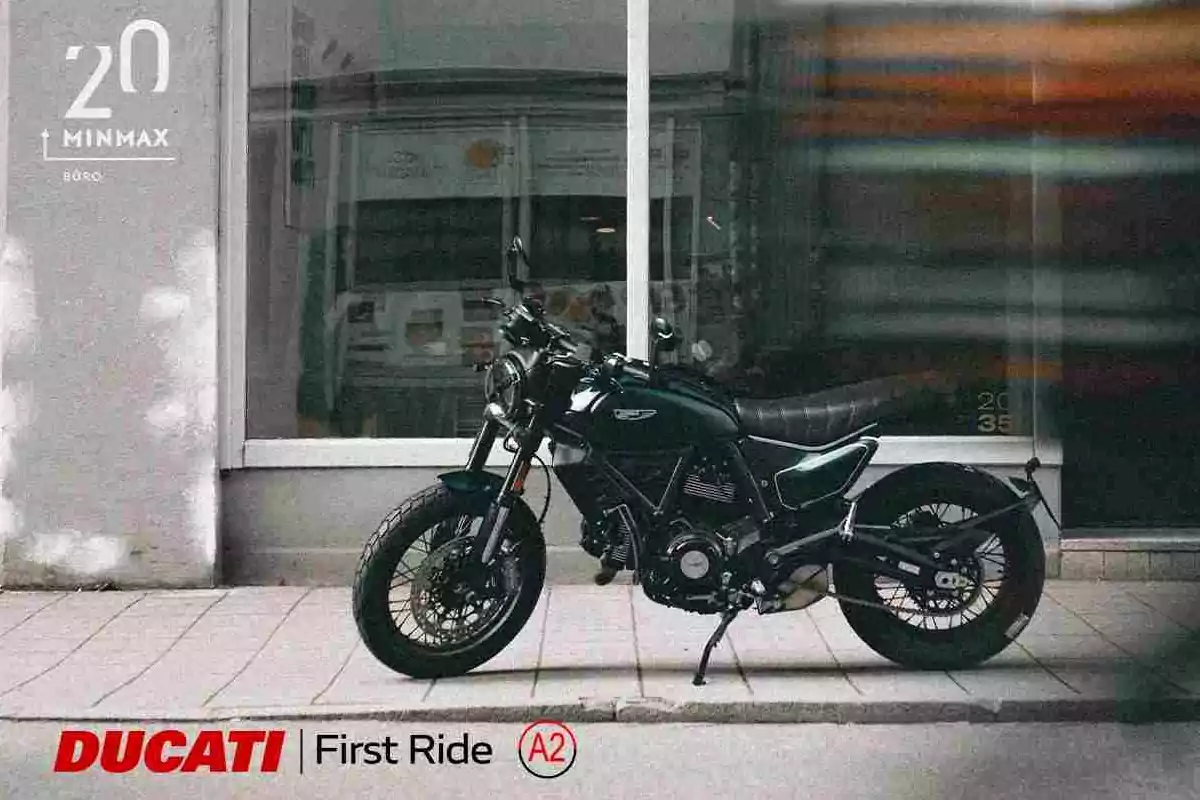 Motocicleta Ducati estacionada en una acera frente a una ventana grande de un edificio Motocicleta Ducati estacionada en una acera frente a una ventana grande de un edificio
