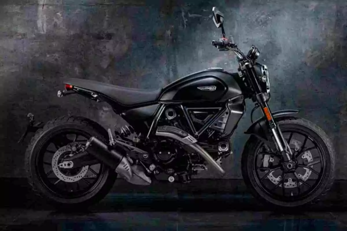 Motocicleta negra de estilo moderno estacionada frente a una pared oscura Motocicleta negra de estilo moderno estacionada frente a una pared oscura