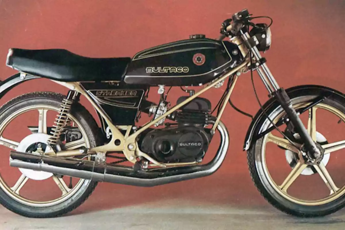 Motocicleta clásica Bultaco Streaker de color negro con detalles dorados sobre un fondo rojo Motocicleta clásica Bultaco Streaker de color negro con detalles dorados sobre un fondo rojo