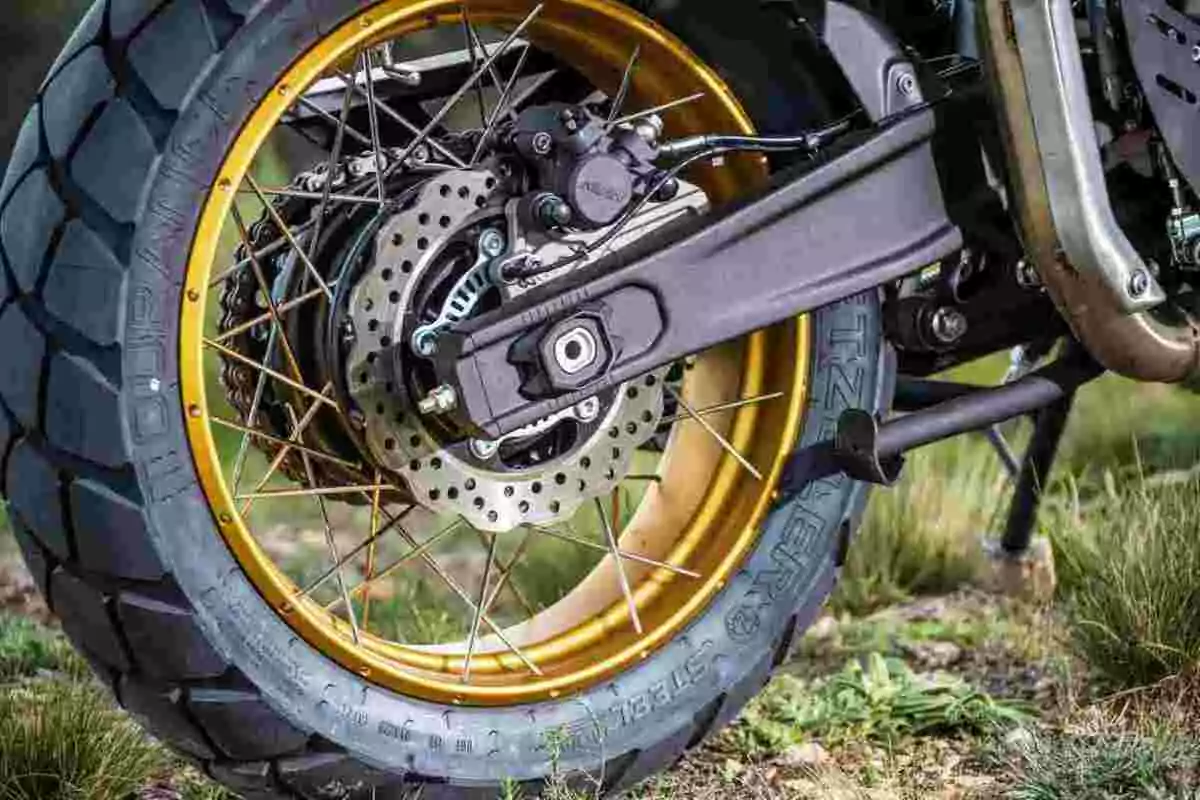 Rueda trasera de motocicleta con llanta dorada y freno de disco en un terreno de pasto Rueda trasera de motocicleta con llanta dorada y freno de disco en un terreno de pasto