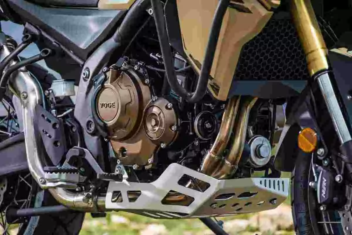 Detalle del motor y chasis de una motocicleta con protección metálica y componentes visibles Detalle del motor y chasis de una motocicleta con protección metálica y componentes visibles