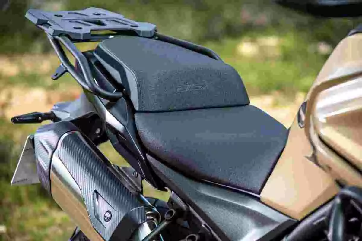 Asiento de motocicleta con portaequipaje trasero y escape visible en un entorno al aire libre Asiento de motocicleta con portaequipaje trasero y escape visible en un entorno al aire libre