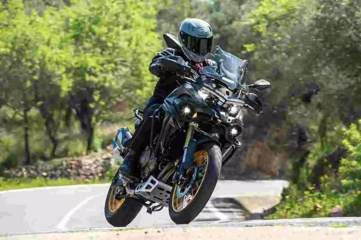 Persona conduciendo una motocicleta deportiva en una carretera rodeada de árboles Persona conduciendo una motocicleta deportiva en una carretera rodeada de árboles