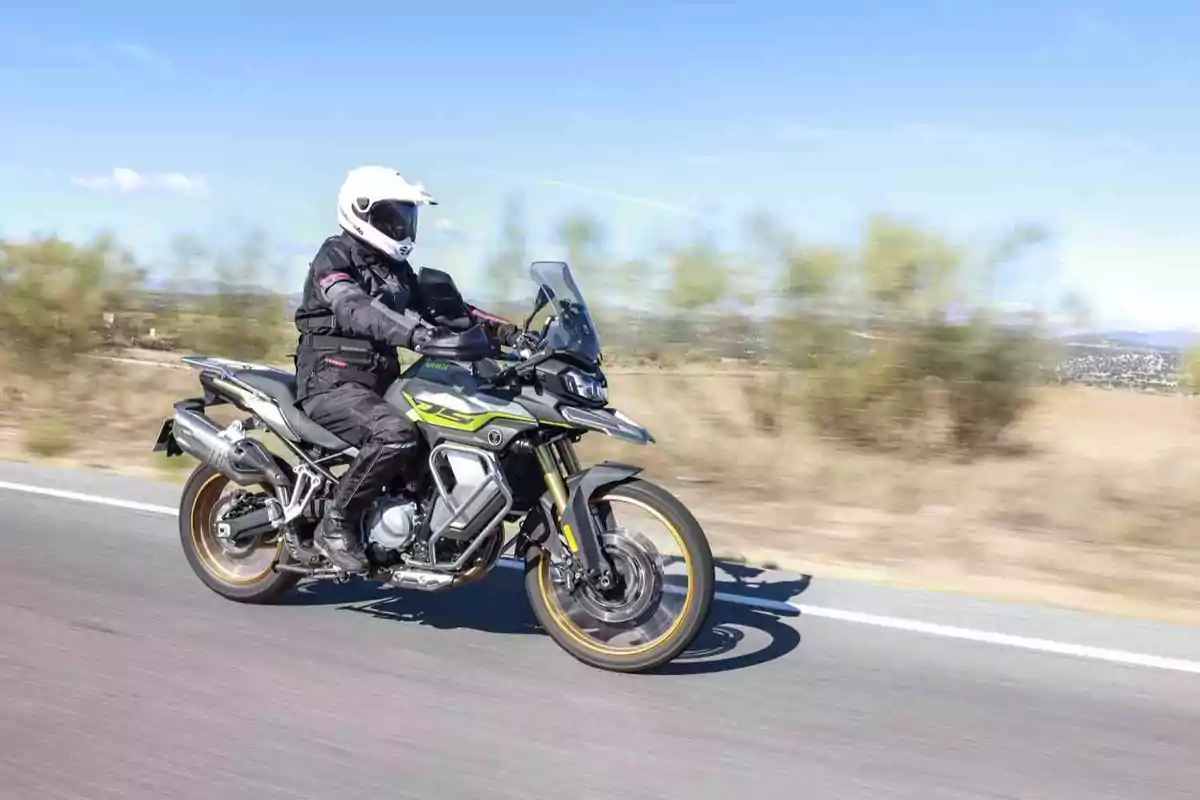 Persona conduint una motocicleta esportiva per carretera amb equip de protecció i casc blanc Persona conduint una motocicleta esportiva per carretera amb equip de protecció i casc blanc