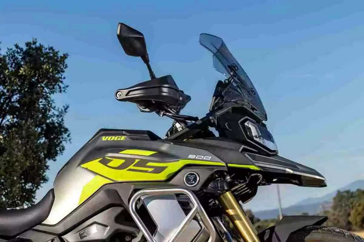 Motocicleta Voge 900 DS de costat amb un fons de cel blau i arbres Motocicleta Voge 900 DS de costat amb un fons de cel blau i arbres