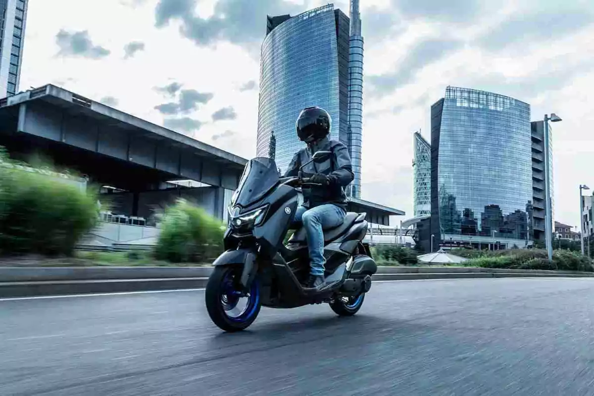Persona conduint una motocicleta en una ciutat moderna amb edificis alts de fons Persona conduint una motocicleta en una ciutat moderna amb edificis alts de fons