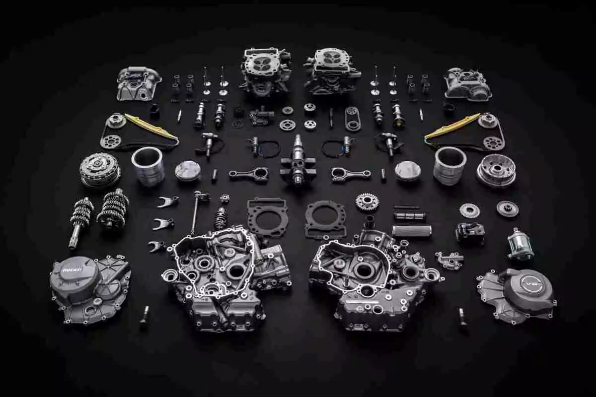 Piezas de un motor de motocicleta completamente desarmado y organizadas sobre una superficie negra Piezas de un motor de motocicleta completamente desarmado y organizadas sobre una superficie negra