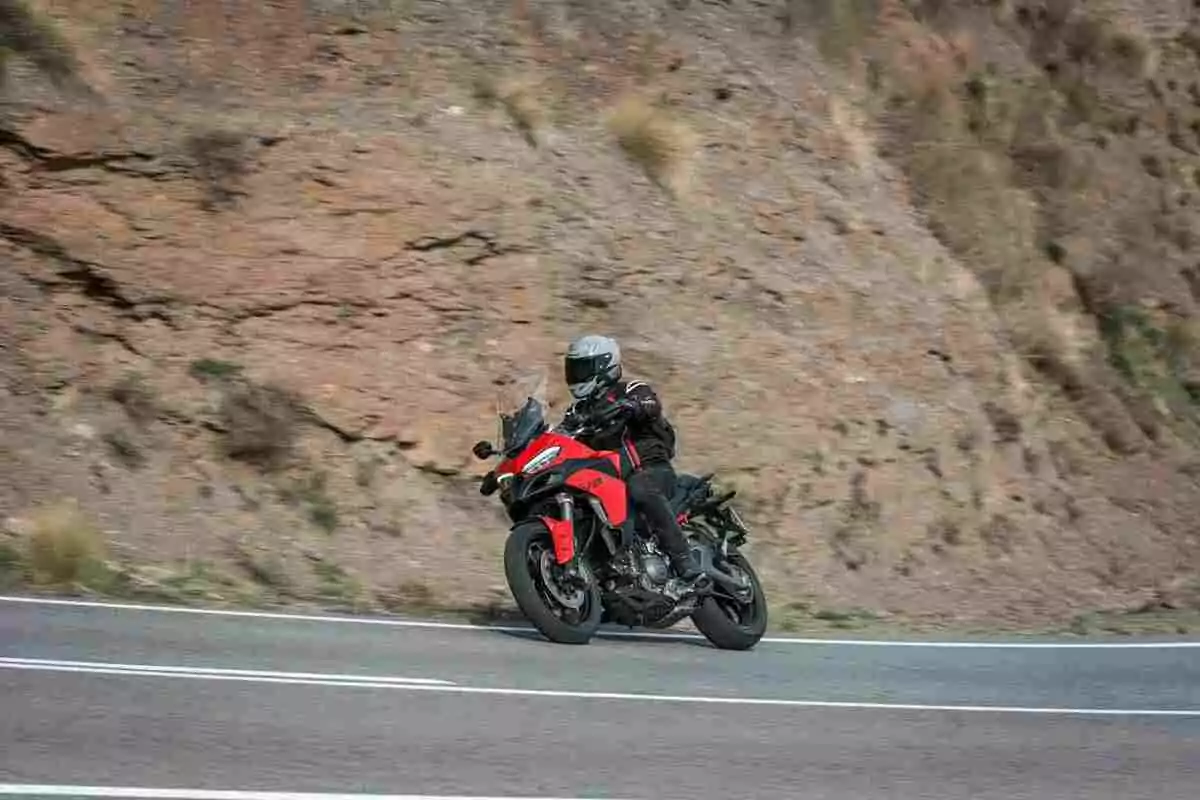 Persona conduciendo una motocicleta roja en una carretera de montaña Persona conduciendo una motocicleta roja en una carretera de montaña