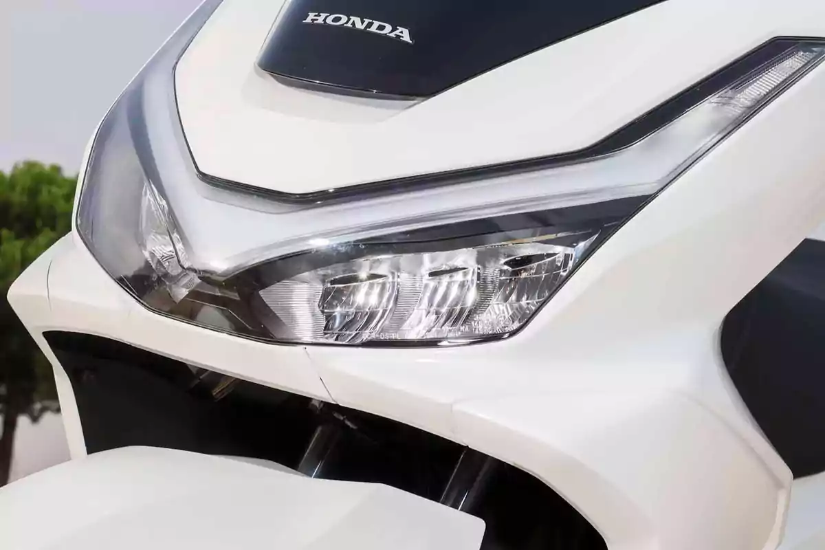 Frente de una motocicleta Honda blanca con faro moderno y diseño aerodinámico Frente de una motocicleta Honda blanca con faro moderno y diseño aerodinámico