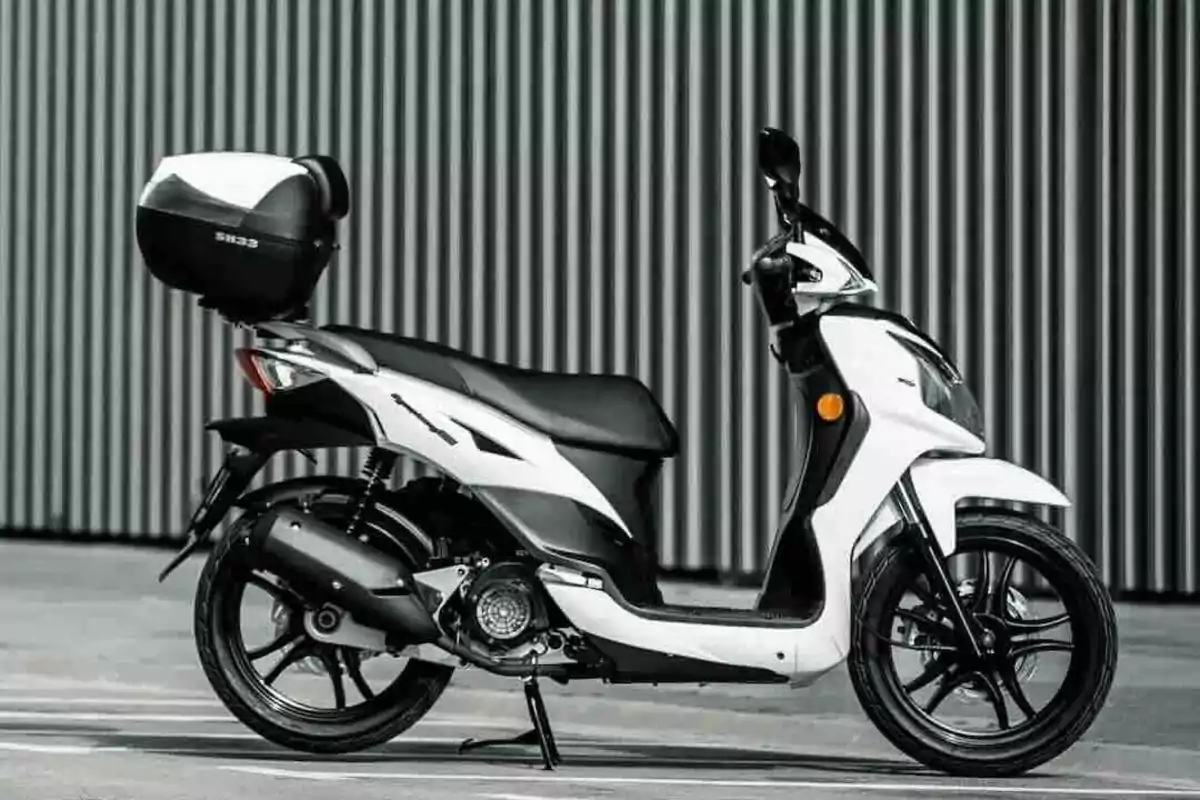 Motocicleta tipo scooter blanca y negra estacionada frente a una pared de láminas verticales Motocicleta tipo scooter blanca y negra estacionada frente a una pared de láminas verticales