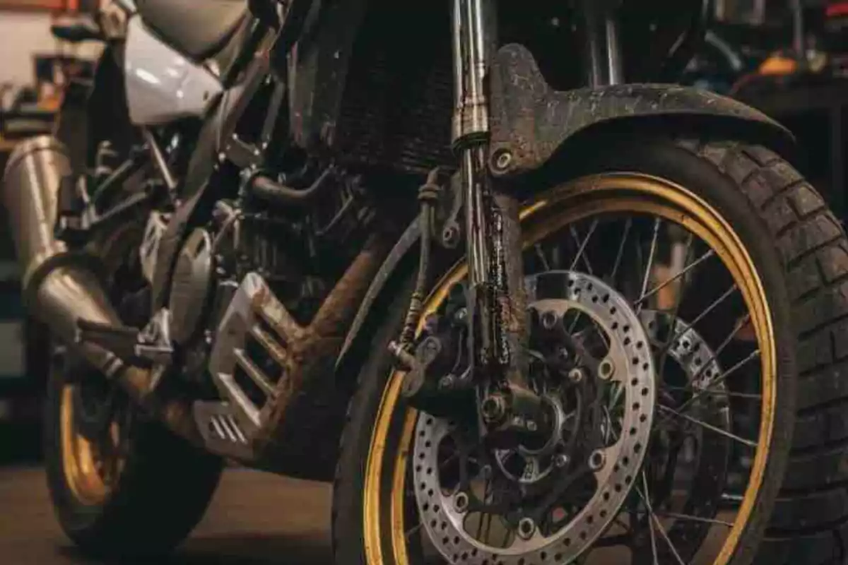 Motocicleta con llantas de borde dorado y freno de disco en un taller Motocicleta con llantas de borde dorado y freno de disco en un taller
