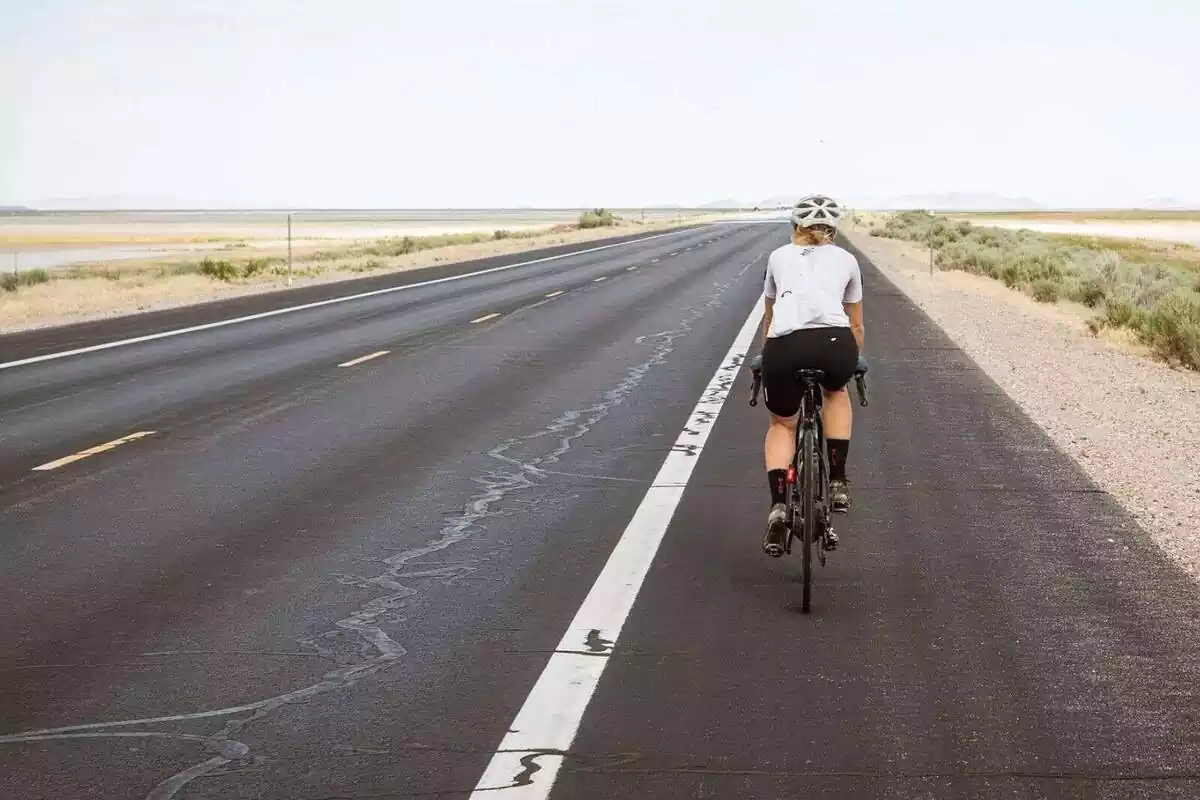 Una persona yendo en bicicleta por una carretera desierta Una persona yendo en bicicleta por una carretera desierta