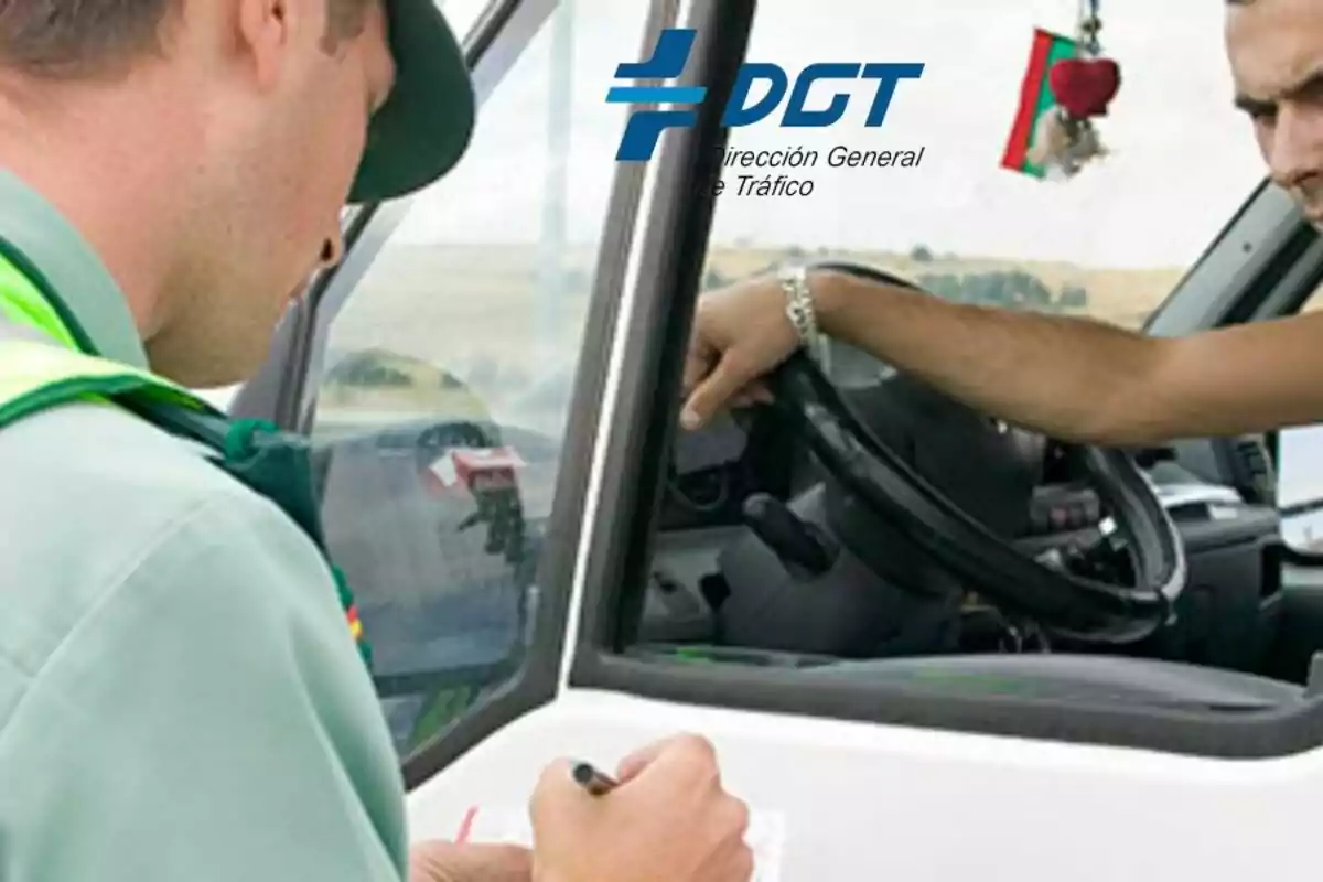 Un agente de la Dirección General de Tráfico (DGT) revisa documentos mientras un conductor espera en su vehículo. Un agente de la Dirección General de Tráfico (DGT) revisa documentos mientras un conductor espera en su vehículo.