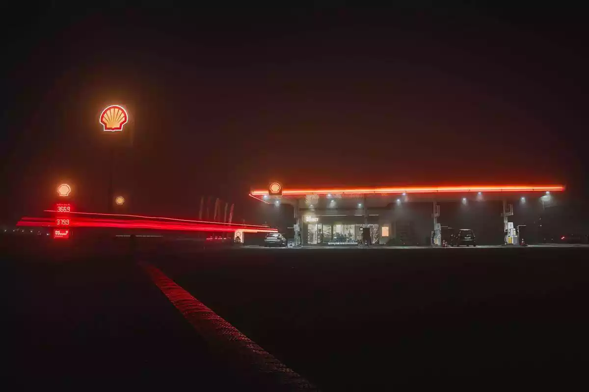 Plano general de gasolinera Shell de noche, iluminada por sus propios carteles Plano general de gasolinera Shell de noche, iluminada por sus propios carteles