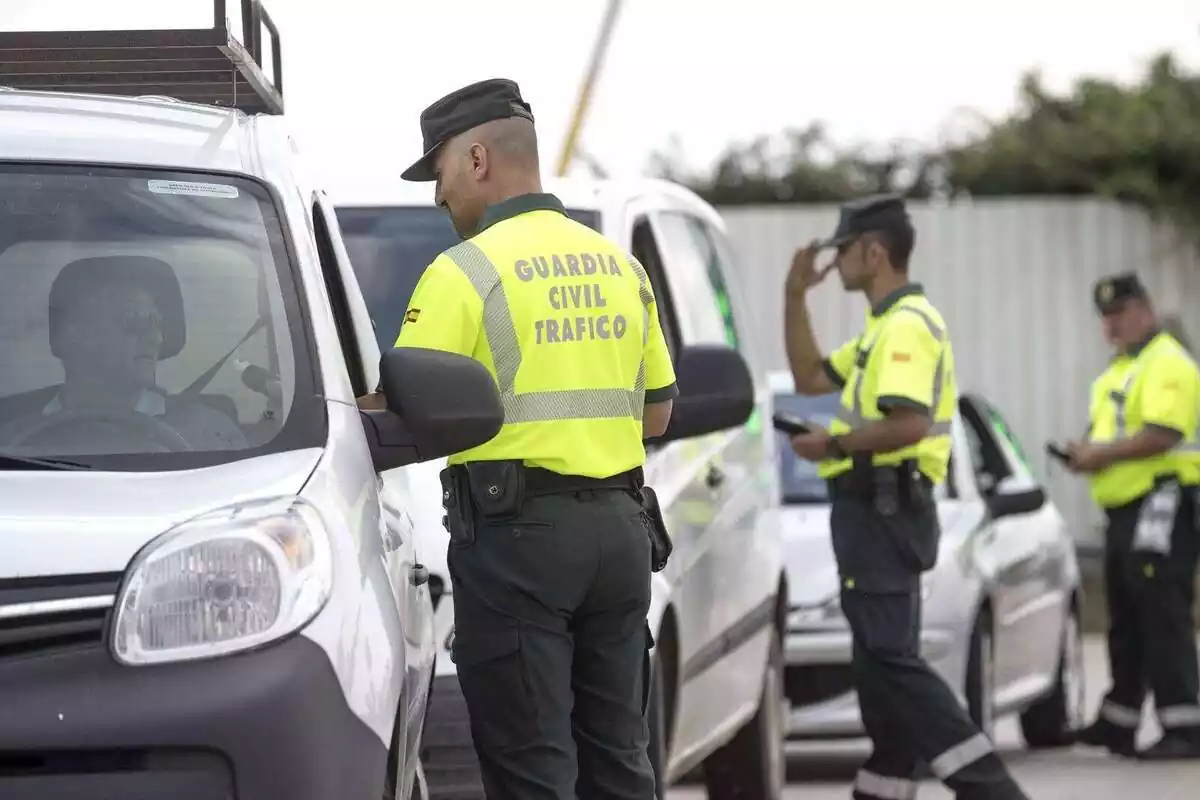 Varios Guardias Civiles de tráfico parando a coches en un control Varios Guardias Civiles de tráfico parando a coches en un control