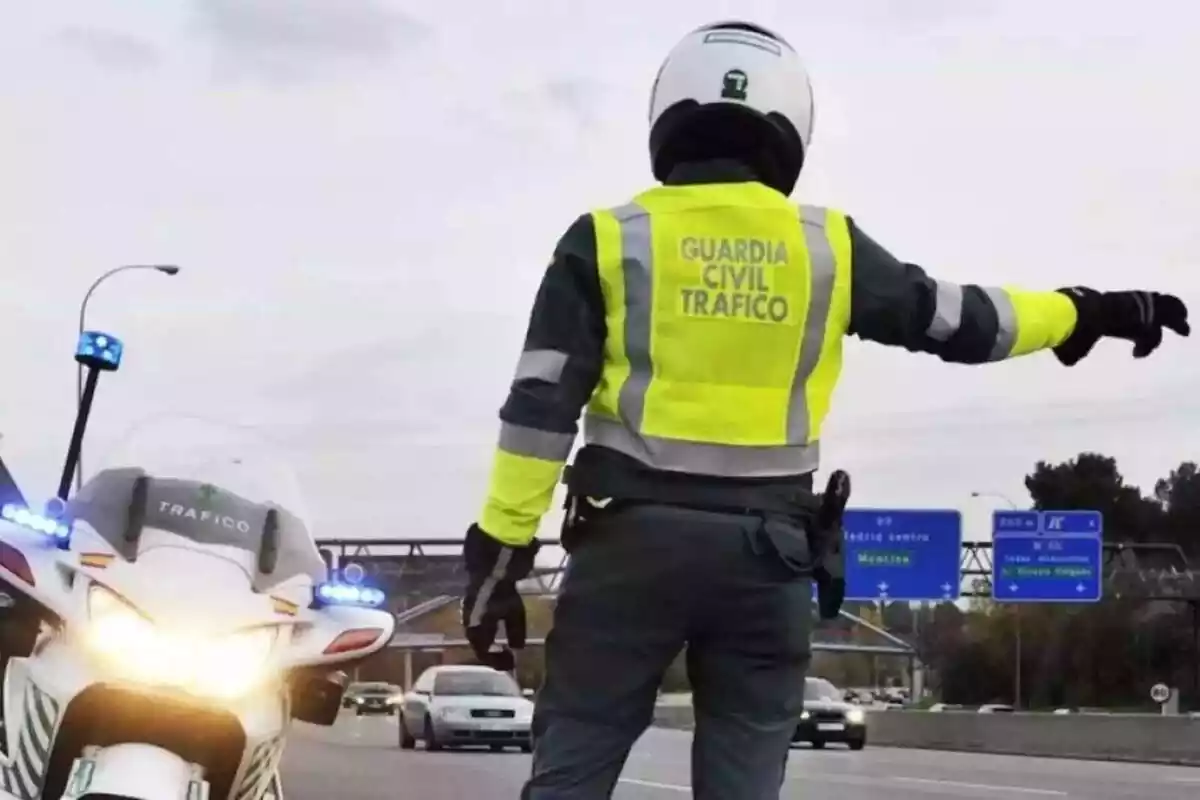 Un Guardia Civil de tràfico en una moto parando a coches en una autovía Un Guardia Civil de tràfico en una moto parando a coches en una autovía