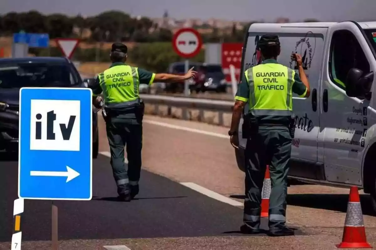 Unos agentes de la Guardia Civil detienen a unos vehículos en un control de carretera, con una señal de la ITV Unos agentes de la Guardia Civil detienen a unos vehículos en un control de carretera, con una señal de la ITV
