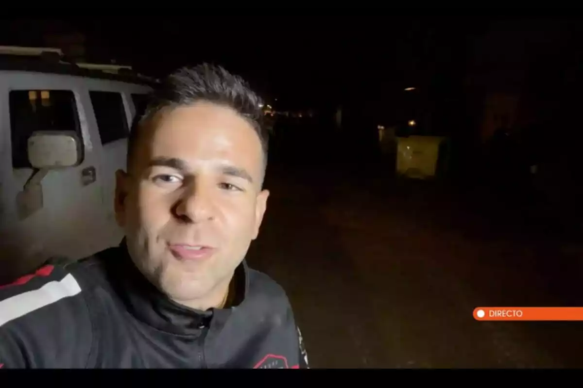 Ángel Gaitán sonriente en una calle oscura con un vehículo blanco al fondo y un letrero que indica "Directo". Captura de 'Horizonte'