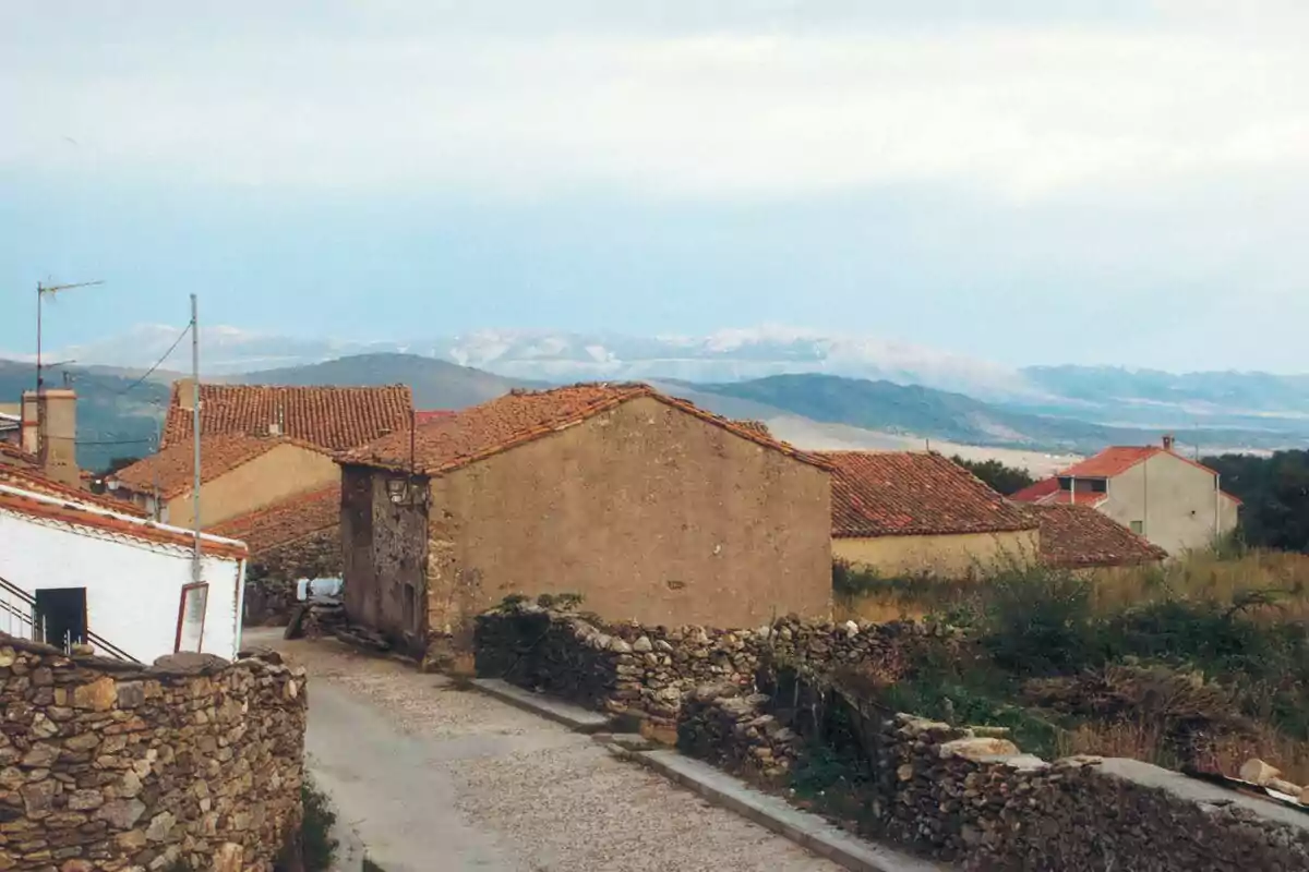 Vista de un pueblo con casas de tejados rojos y montañas al fondo. Vista de un pueblo con casas de tejados rojos y montañas al fondo.