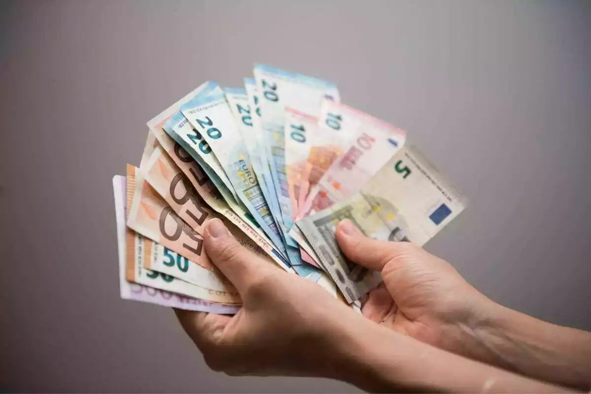 Dos manos de una persona mostrando diferentes tipos de billete de euro en forma de abanico Dos manos de una persona mostrando diferentes tipos de billete de euro en forma de abanico