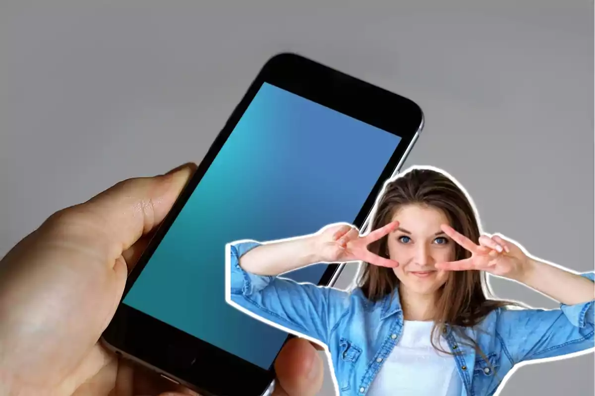 Persona haciendo un gesto de paz con los dedos junto a un teléfono móvil. Persona haciendo un gesto de paz con los dedos junto a un teléfono móvil.