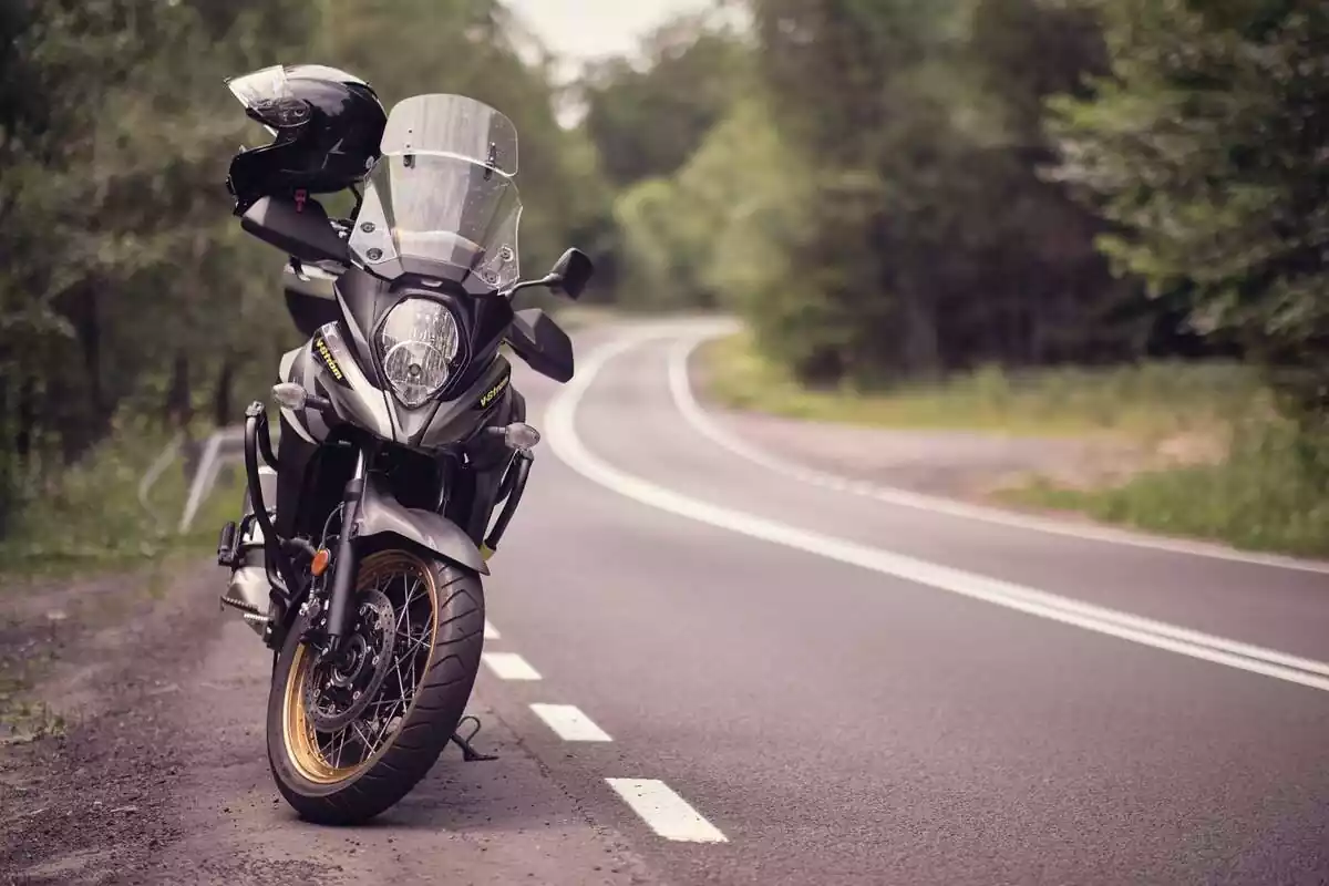 Imagen frontal de una moto que tiene un casco apoyado en el asiento y está situada en el arcén de una carretera