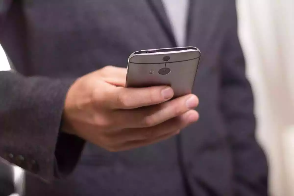 Un home agafant un telèfon mòbil amb una mà Un home agafant un telèfon mòbil amb una mà