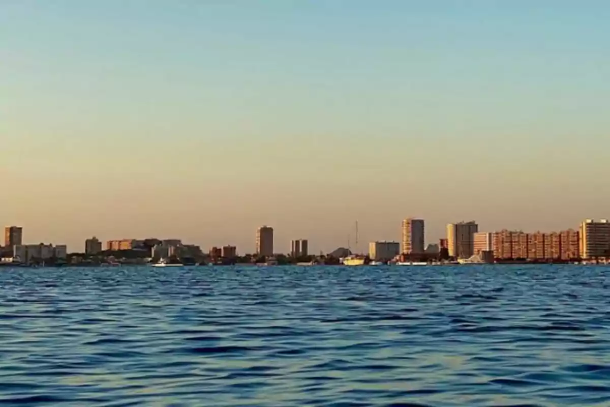 Vista de una ciudad costera con edificios altos al atardecer y el mar en primer plano. Vista de una ciudad costera con edificios altos al atardecer y el mar en primer plano.