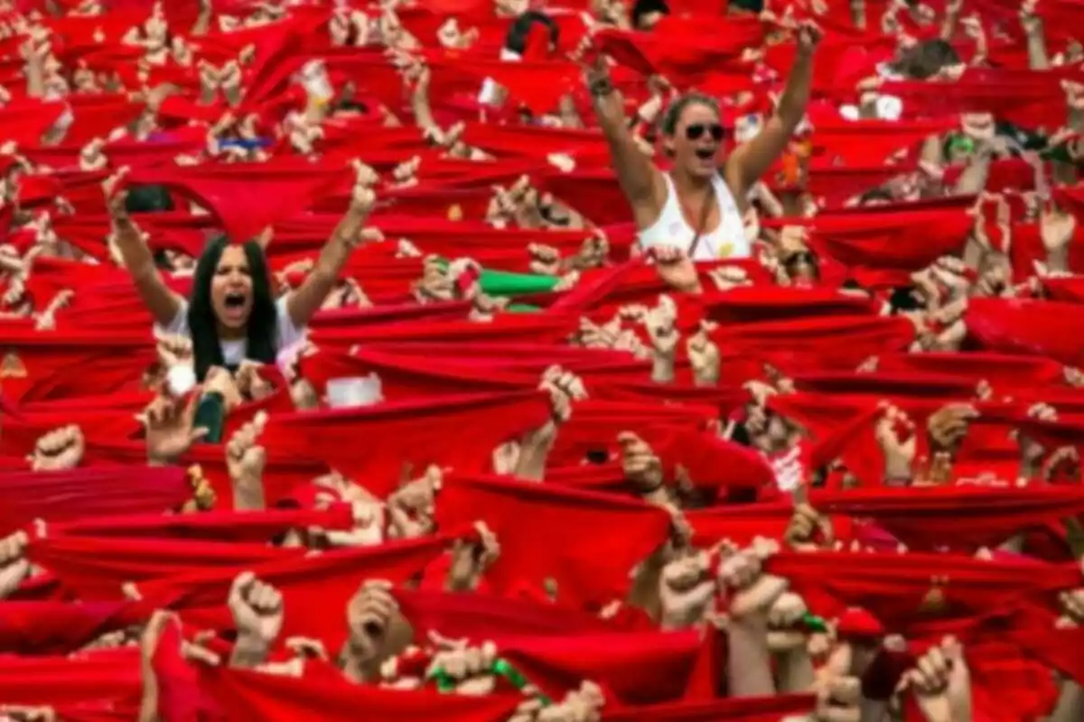 Multitud de personas levantando pañuelos rojos en un evento festivo.