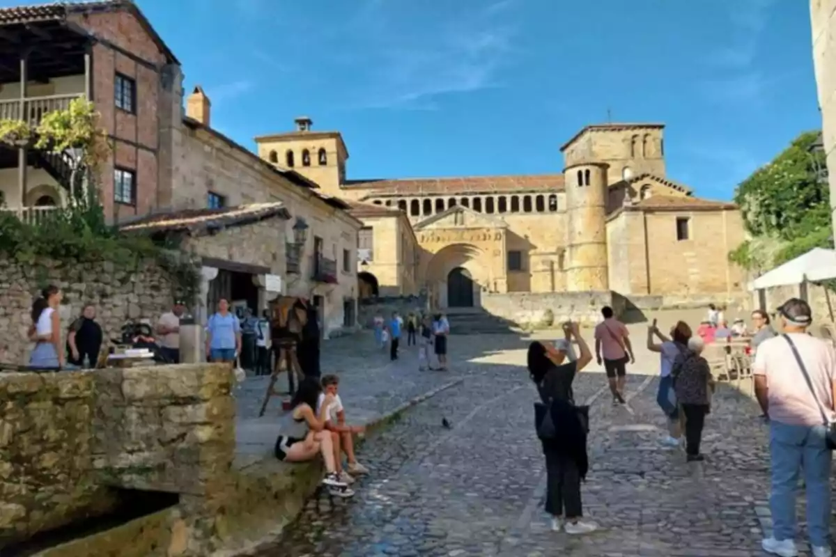 Una plaça empedrada amb turistes i una església antiga al fons. Una plaça empedrada amb turistes i una església antiga al fons.