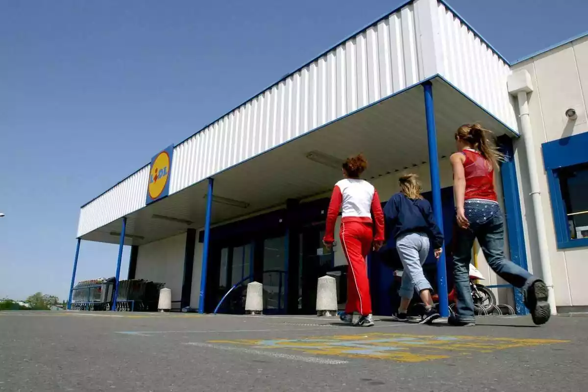 Tres clientas caminan en dirección a la entrada de la tienda Lidl Tres clientas caminan en dirección a la entrada de la tienda Lidl