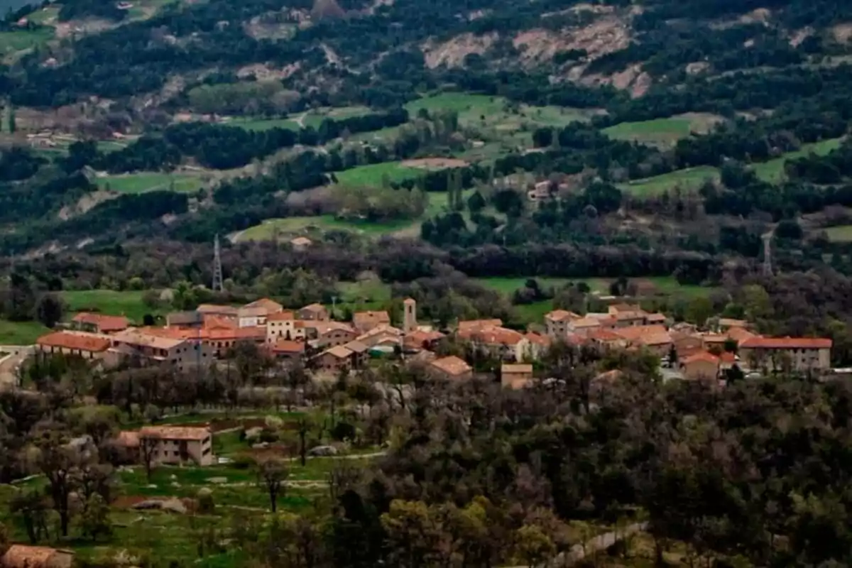 Vista panorámica de un pequeño pueblo rodeado de colinas verdes y bosques. Vista panorámica de un pequeño pueblo rodeado de colinas verdes y bosques.